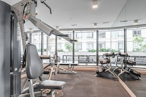 Una palestra con attrezzature per esercizi, ampie finestre e vista sull'esterno.