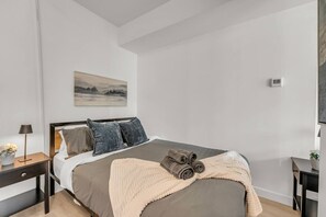 A modern bedroom with a bed, a nightstand, a lamp, and a painting on the wall. - *World Cup* Stylish Downtown Apartment With Gym (Toronto)