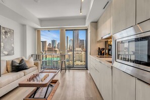 A modern kitchen with a large window, a dining area with a chessboard, and a city view. - *World Cup* Stylish Downtown Apartment With Gym (Toronto)