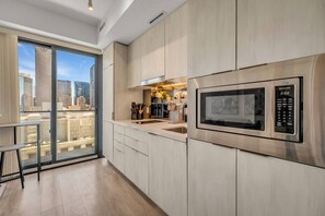 A modern kitchen with a stainless steel microwave, a built-in oven, and a city view through large windows. - *World Cup* Stylish Downtown Apartment With Gym (Toronto)
