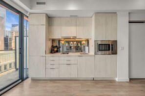 A modern kitchen with a large window, a built-in microwave, and a view of the cityscape. - *World Cup* Stylish Downtown Apartment With Gym (Toronto)