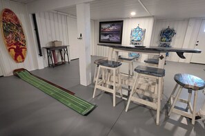 Ein Zimmer mit Barbereich, Hockern, einem Fernseher und einem großen abstrakten Gemälde.