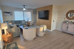 Ein Wohnzimmer mit einer Couch, einem Couchtisch und einem an einer Holzwand montierten Fernseher.