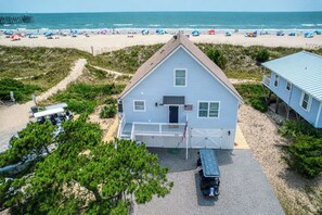 Ein zweistöckiges Haus mit Veranda, Garage und Blick auf den Strand.