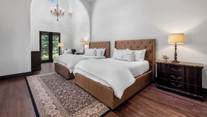 Ein Schlafzimmer mit zwei Betten, einer Kristallleuchter, einem Deckenventilator, einem Nachttisch und einer Kommode.