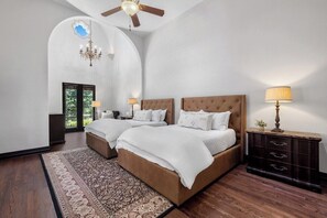Ein Schlafzimmer mit zwei Betten, einer Kristallleuchter, einem Deckenventilator, einem Nachttisch und einer Kommode.