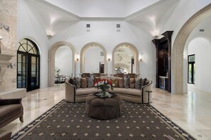 A spacious living room with a beige sofa, a patterned rug, and a fireplace. - Blanco River estate + 2 pools + court (Wimberly)