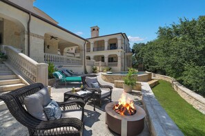 An outdoor patio with wicker furniture, a fire pit, and a pool area. - Blanco River estate + 2 pools + court (Wimberly)