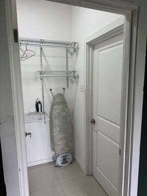A small laundry room with a drying rack, an ironing board, and a washing machine. - Hope Oasis (Kingston)