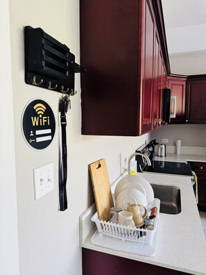 A kitchen with a dish rack holding dishes, a WiFi sign, and a black hanging organizer. - Hope Oasis (Kingston)