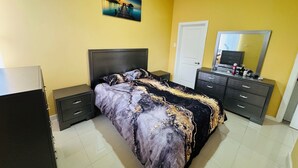 A bedroom with a bed, nightstands, a dresser, a mirror, and a painting on the wall. - Hope Oasis (Kingston)
