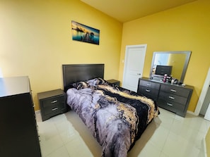 Ein Schlafzimmer mit einem Bett, Nachttischen, einer Kommode, einem Spiegel und einem Bild an der Wand.