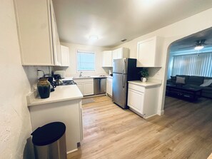 A modern kitchen with white cabinets, a stainless steel refrigerator, and a dining area with a dark-colored sofa. - Serene 3-bedroom house with AC in charming St. Petersburg (St. Petersburg)