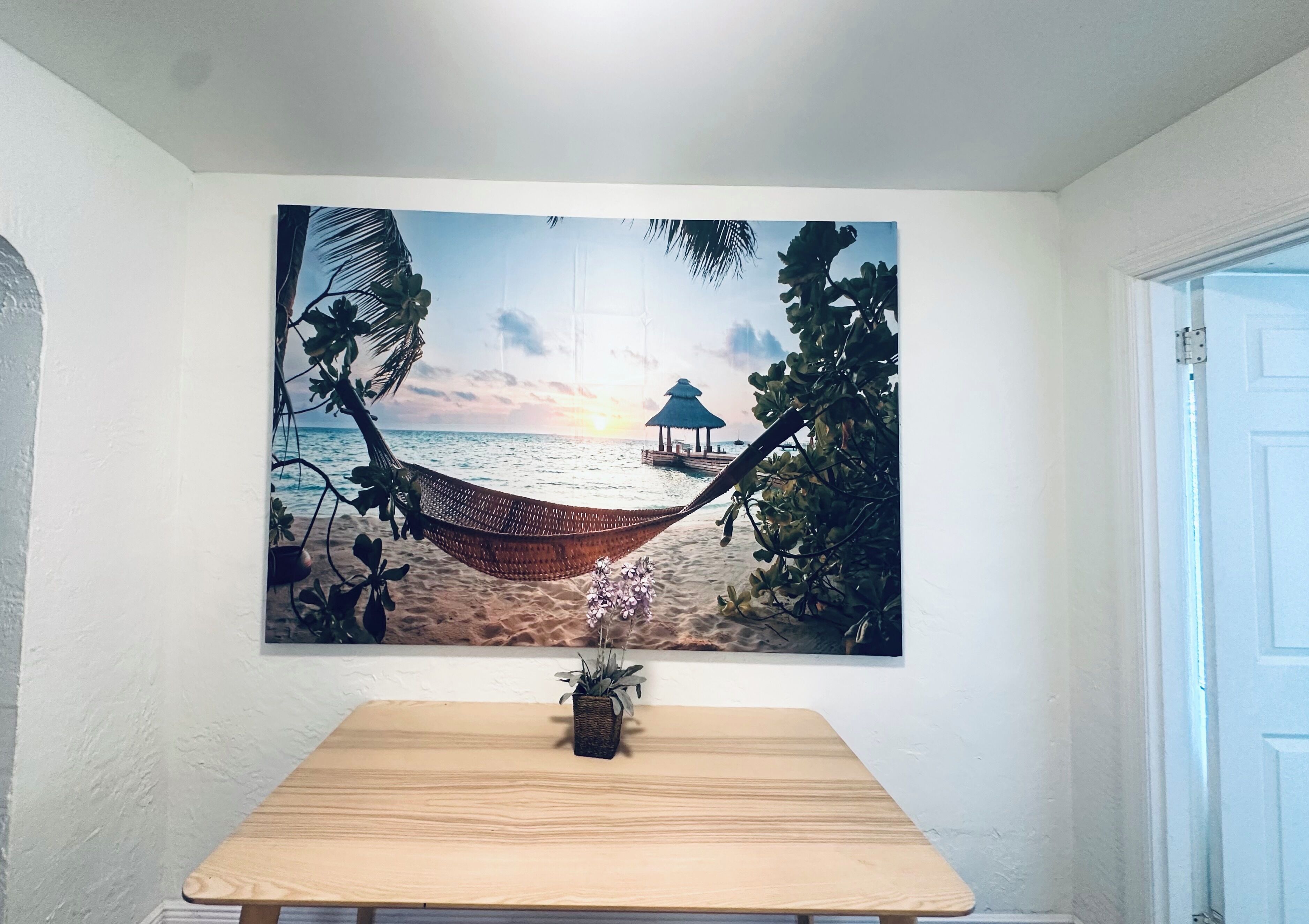 A beach scene with a hammock, palm trees, and a hut.