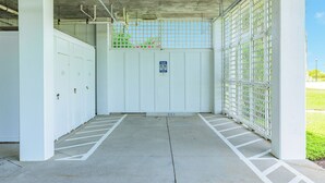 Une entrée de parking avec une barrière, un sol en béton et un panneau indiquant les règles de stationnement.