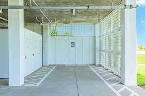 Einfahrt zu einer Tiefgarage mit befahrbarer Schranke, Betonboden und einem Schild mit Parkregeln.