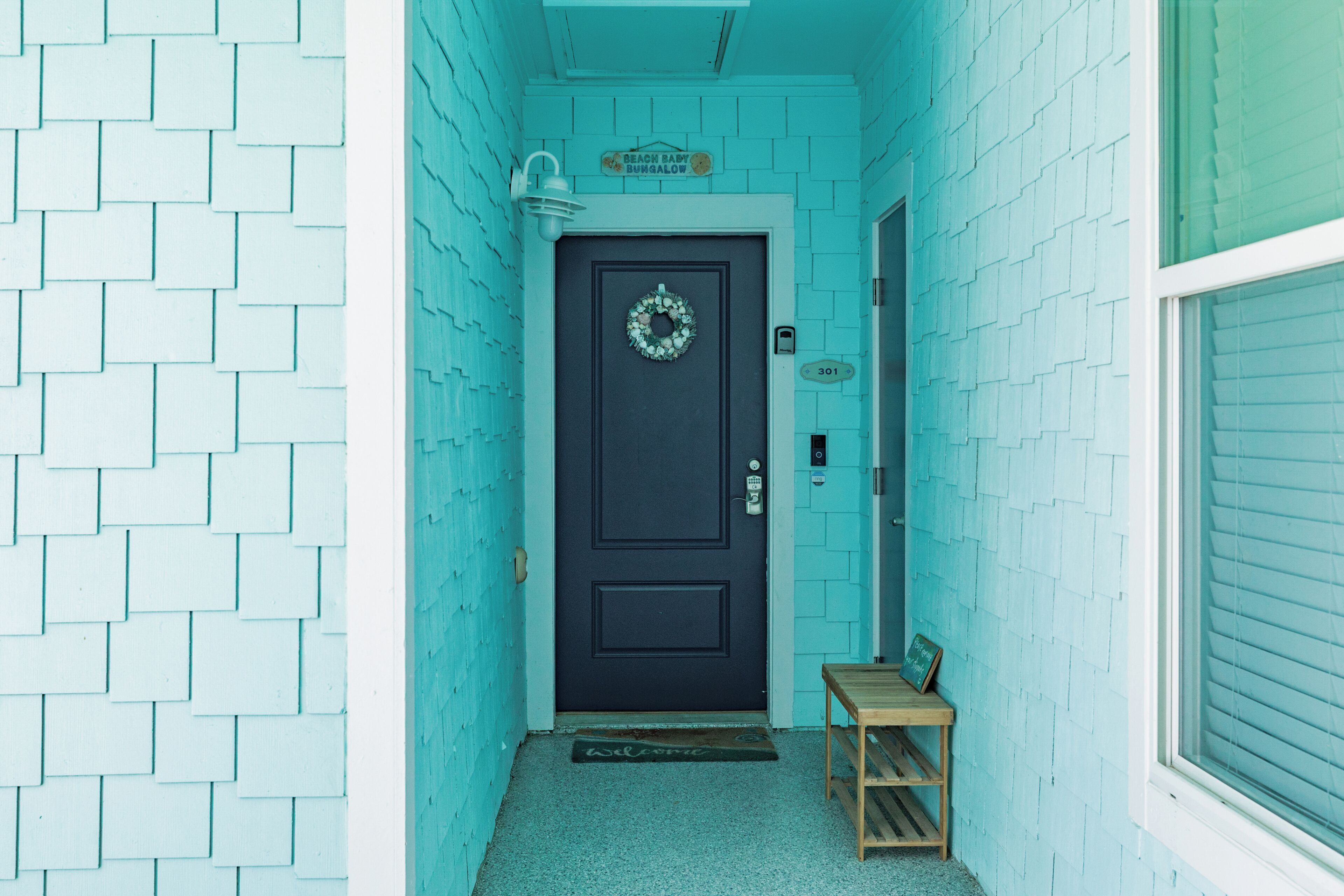 A narrow hallway with a dark door, a small bench, and a welcome mat.
