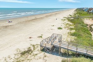 Ein Strand mit einer hölzernen Prominade, die zu einer Sandfläche führt.