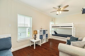 Ein Zimmer mit Etagenbett, Schreibtisch mit Stauraum, Lampe und Deckenventilator.