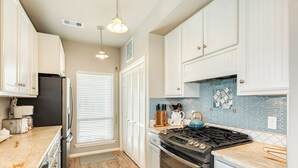 A kitchen with white cabinets, a stove, and a coffee maker. - Close to the Sand w/ Showstopping Views & Wonderful Amenities - Dog Friendly! (Galveston)