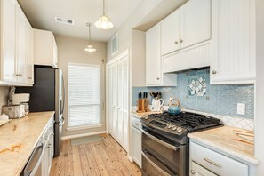 A kitchen with white cabinets, a stove, and a coffee maker. - Close to the Sand w/ Showstopping Views & Wonderful Amenities - Dog Friendly! (Galveston)