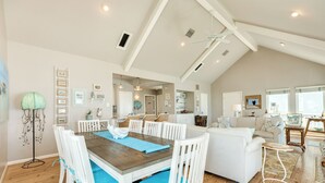 A spacious living area with a high ceiling, a dining table with chairs, a sofa set, and a kitchen in the background. - Close to the Sand w/ Showstopping Views & Wonderful Amenities - Dog Friendly! (Galveston)