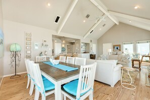 A spacious living area with a high ceiling, a dining table with chairs, a sofa set, and a kitchen in the background. - Close to the Sand w/ Showstopping Views & Wonderful Amenities - Dog Friendly! (Galveston)