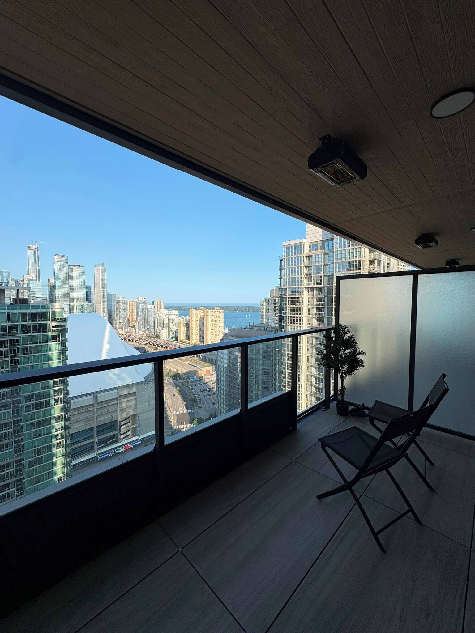 A modern balcony with a city view, a potted plant, and a foldable chair.