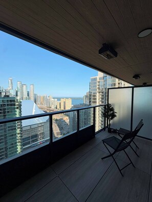 Ein moderner Balkon mit Blick auf die Stadt, einer Topfpflanze und einem Klappstuhl.