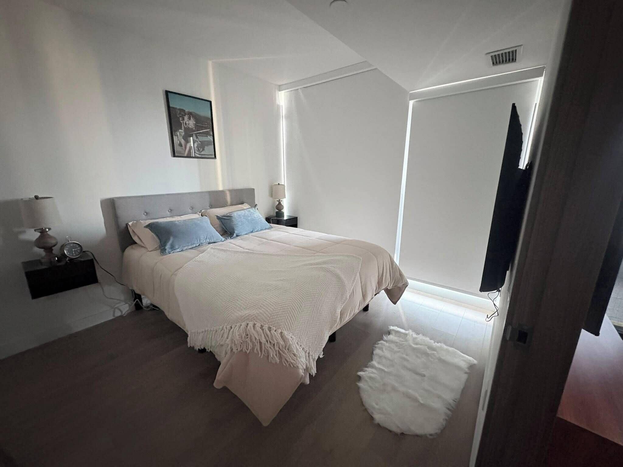 A bedroom with a bed, bedside tables, a lamp, a picture on the wall, and a door.