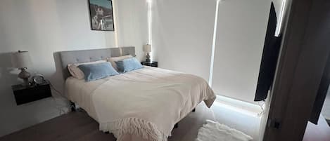 A bedroom with a bed, bedside tables, a lamp, a picture on the wall, and a door.
