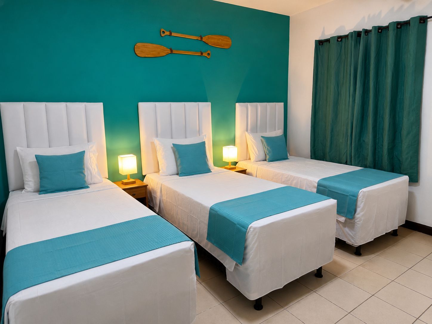 Quarto de hotel com duas camas, paredes verde-água e uma decoração com remo de madeira.