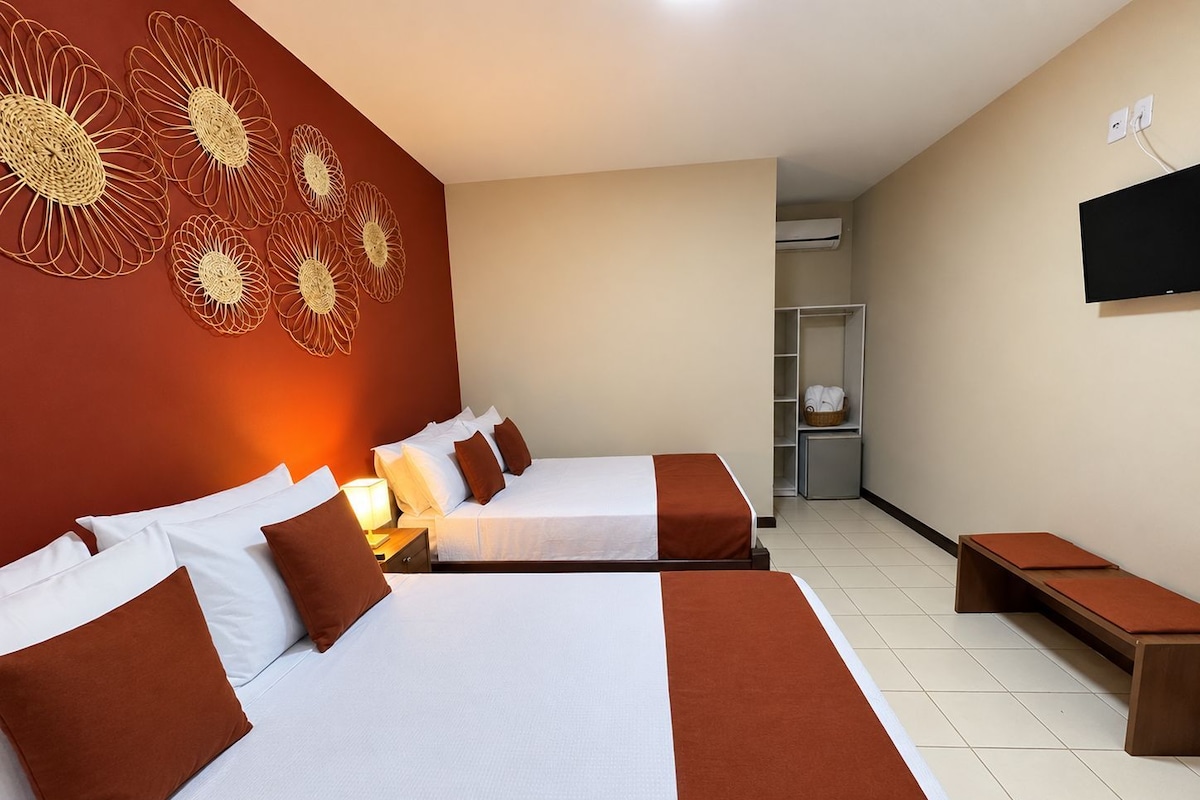 Una habitación de hotel con dos camas, un televisor montado en la pared y un armario.