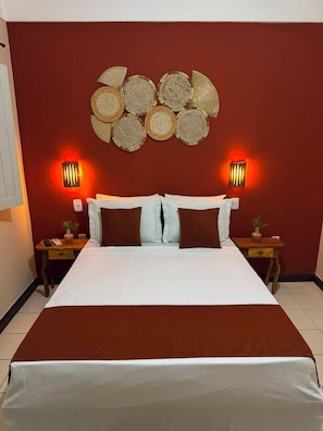 A hotel room with a large bed, two bedside tables with lamps, and a decorative wall hanging above the bed. - Pousada Lagoas de Guarajuba (Camaçari)