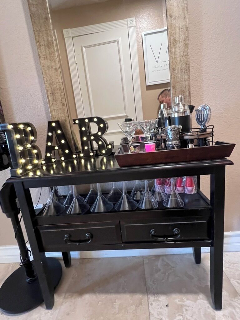 A bar setup with illuminated letters spelling 'BAR' and a tray with glasses and bottles.