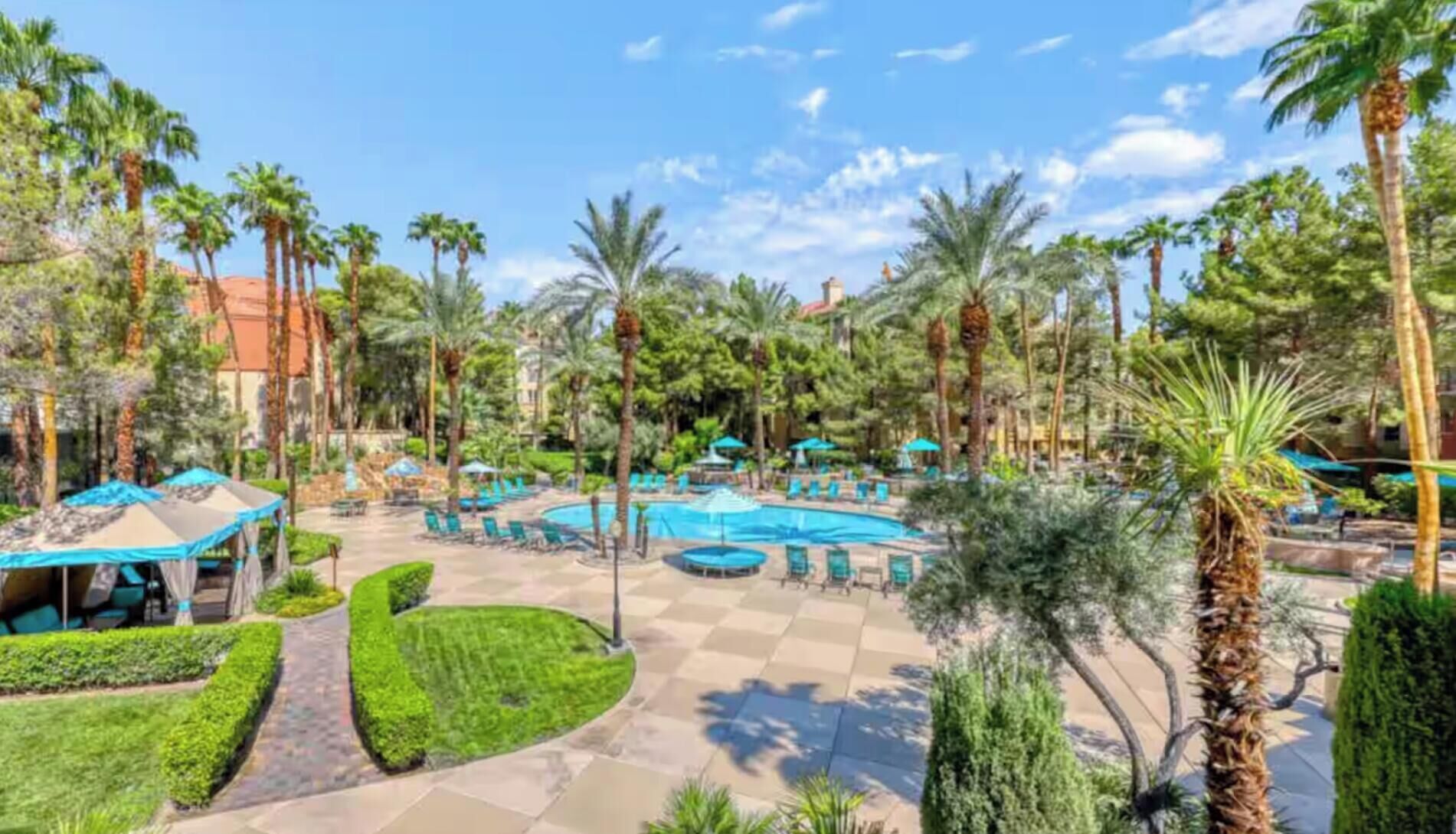 A resort with a pool area, palm trees, and lounge chairs.