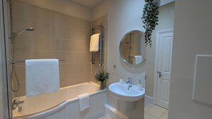 A bathroom with a bathtub, a sink, a mirror, and a shower.