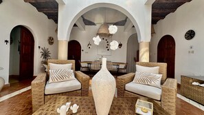 A spacious interior with two wicker sofas, a central decorative vase, and a dining area with a table and chairs. - Villa under the trade winds (Essaouira)