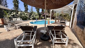A poolside area with lounge chairs, a pergola, and a pool. - Villa under the trade winds (Essaouira)