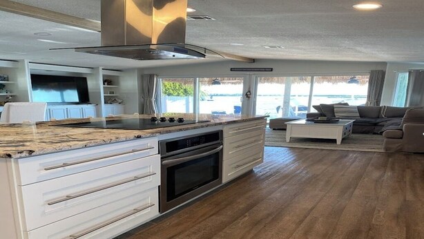 Una cocina moderna con una isla central, horno empotrado y un amplio ventanal con vistas al exterior.
