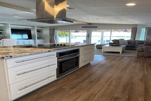 A modern kitchen with a central island, built-in oven, and a large window offering a view of the outdoors. - Baydream Believers Retreat (Tavernier)