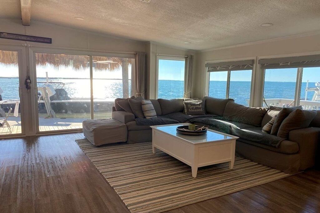 A living room with a large window, a sofa, a coffee table, and a view of the sea.