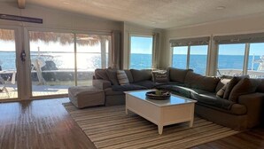Una sala de estar con un ventanal grande, un sofá, una mesa de centro y vista al mar.