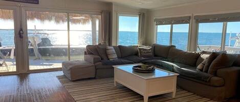 A living room with a large window, a sofa, a coffee table, and a view of the sea.