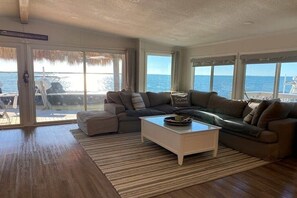 Ein Wohnzimmer mit großem Fenster, einer Couch, einem Couchtisch und Blick auf das Meer.