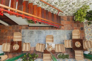 A rooftop terrace with a wooden staircase, wicker furniture, and potted plants. - Casa Aura Hotel (Bogotá)
