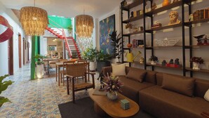A spacious living area with a high ceiling, a staircase, and a bookshelf filled with books and decorative items.