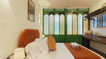 Habitación de hotel con cama, lámpara de noche, puerta verde con paneles de vidrio decorativos y cómoda de madera con espejo.