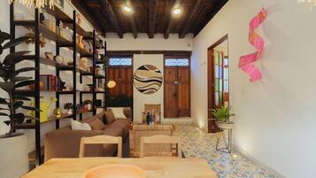 Una sala de estar acogedora con una mesa de madera, un sofá y una estantería llena de libros y objetos decorativos.