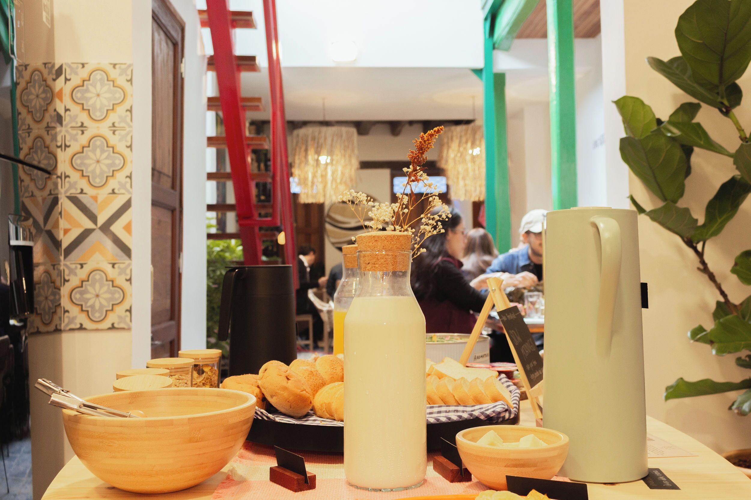 A dining area with a table set for a meal, including bread, a bottle of drink, and a pitcher.